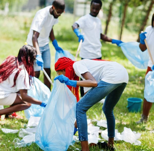 groupe-de-volontaires-africains-heureux-avec-des-sacs-a-ordures-zone-de-nettoyage-dans-le-parc-afrique-benevolat-charite-personnes-et-concept-ecologique-min